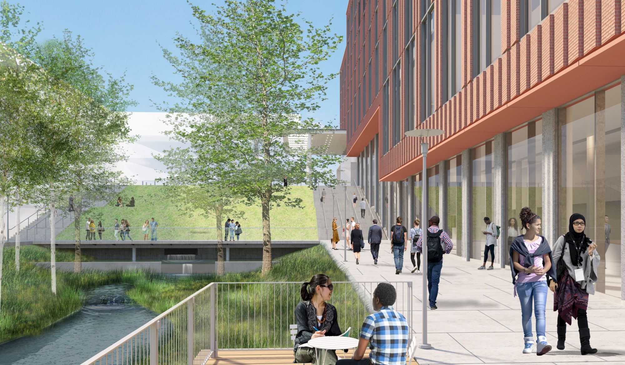 People are walking and sitting near a modern building with glass walls, a grassy hill, and a small stream, on a sunny day.